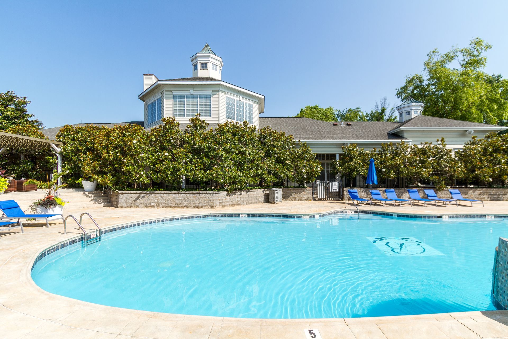 Pool with blue water and lounge chairs, next to a building with a white dome. Tour our welcoming Apts Lexington, KY residents enjoy every day.