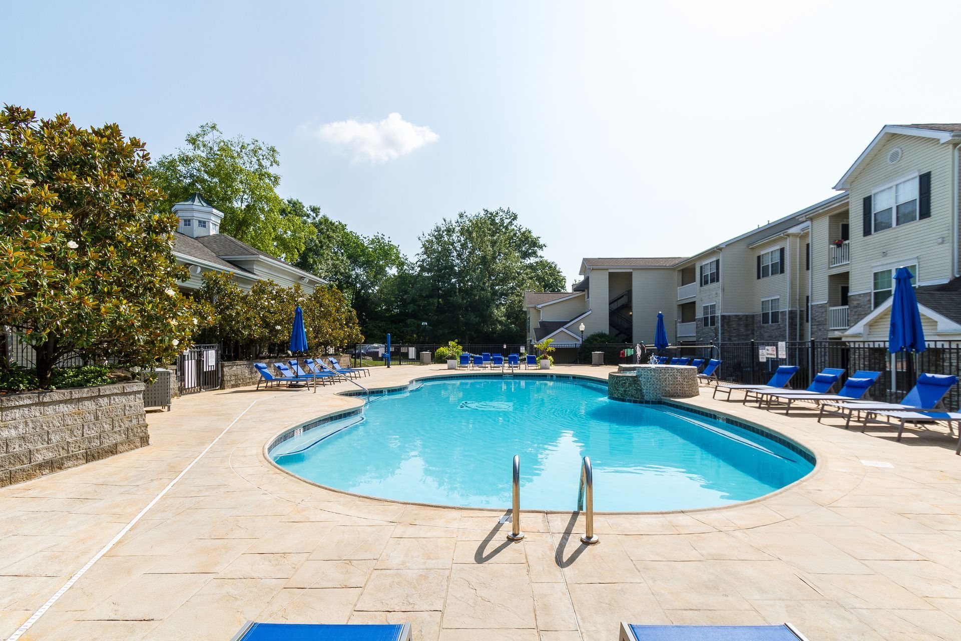 Swimming pool surrounded by lounge chairs and umbrellas, with apartment buildings in the background. Find your ideal layout among our Lexington, KY apartments—book a tour today.