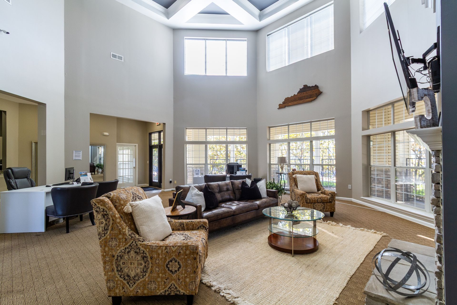 Resident club house high ceilings, large windows, and leather sofa; a Kentucky state-shaped decor. Explore bright and open Lexington, KY rentals with a private community tour.