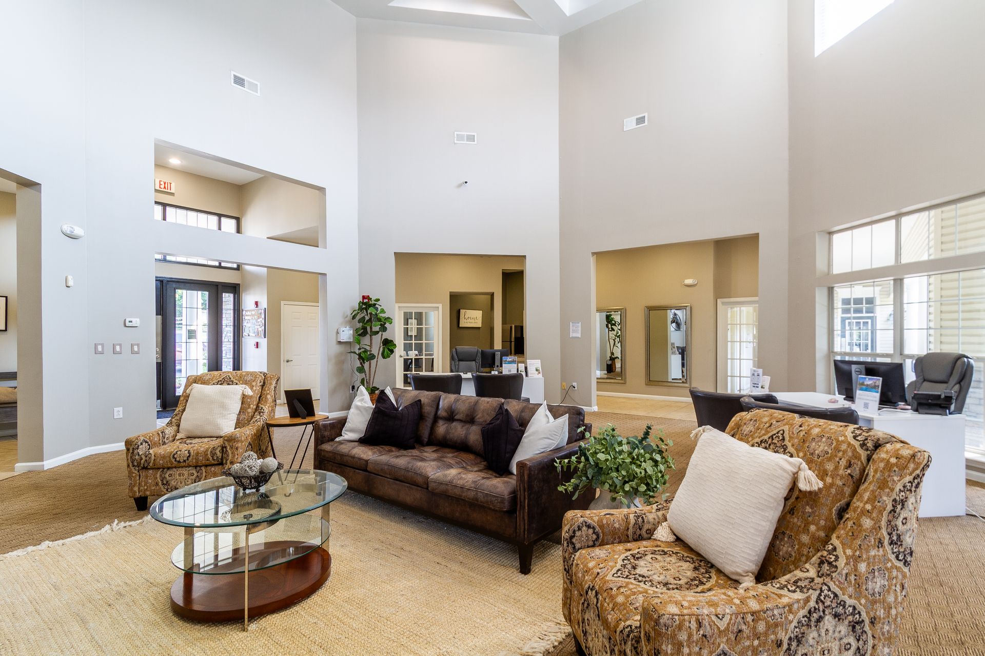 Resident club house with high ceilings, seating, and a glass coffee table. Beige walls, neutral color scheme. Discover comfortable Rentals in Lexington, KY waiting for you at Bridle Creek.