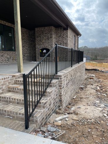 a brick house with a metal railing on the porch and stairs .