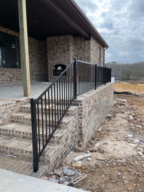 a brick house with a metal railing on the porch and stairs .