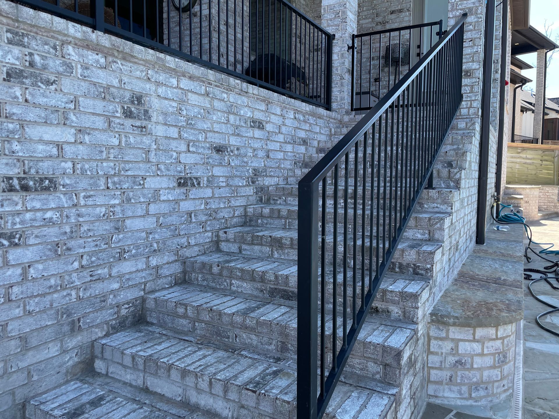 a set of stairs with a black railing on a brick wall