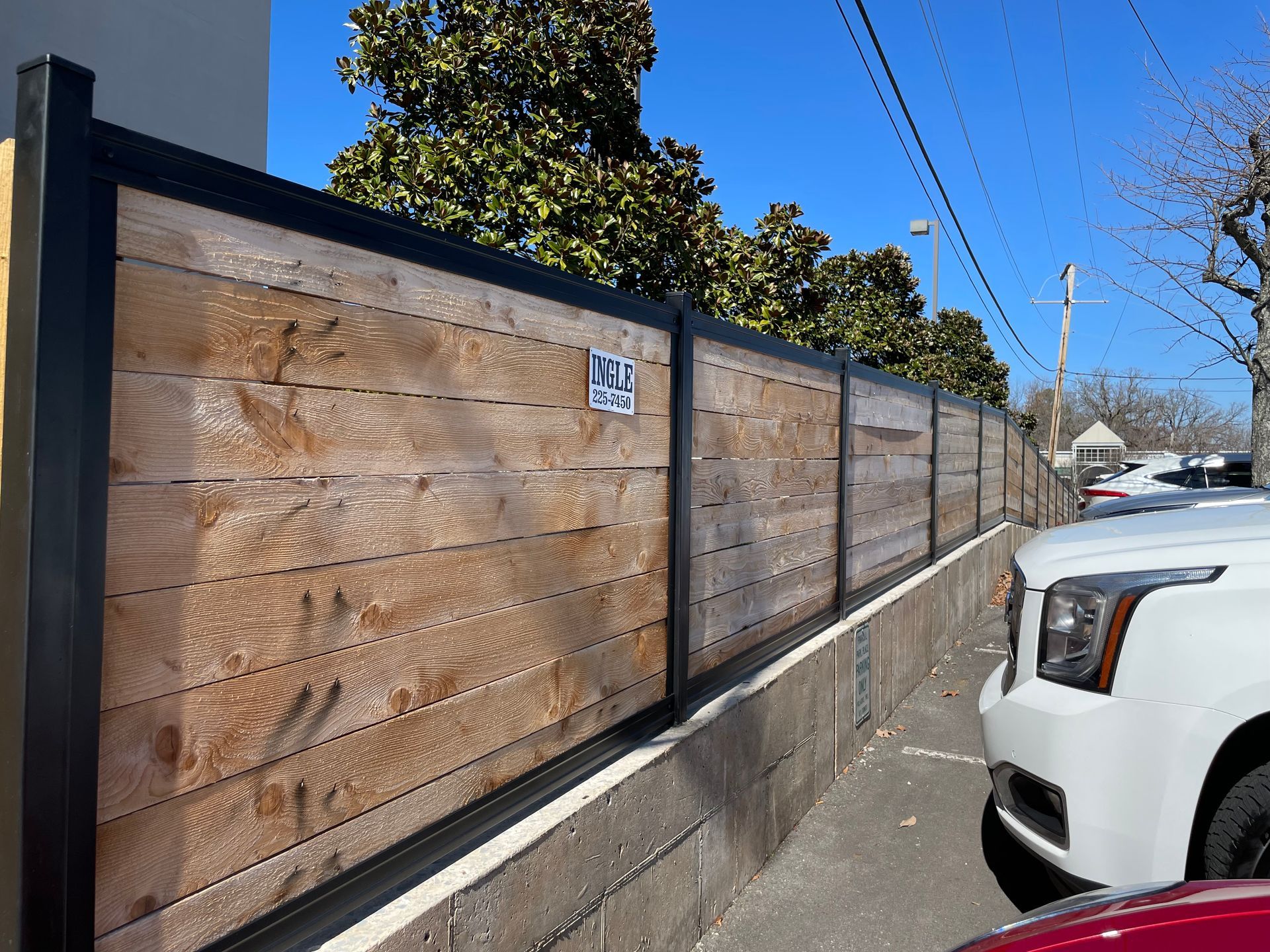 a white car is parked next to a wooden fence