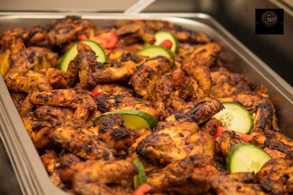 A tray of grilled chicken wings and cucumbers on a table.