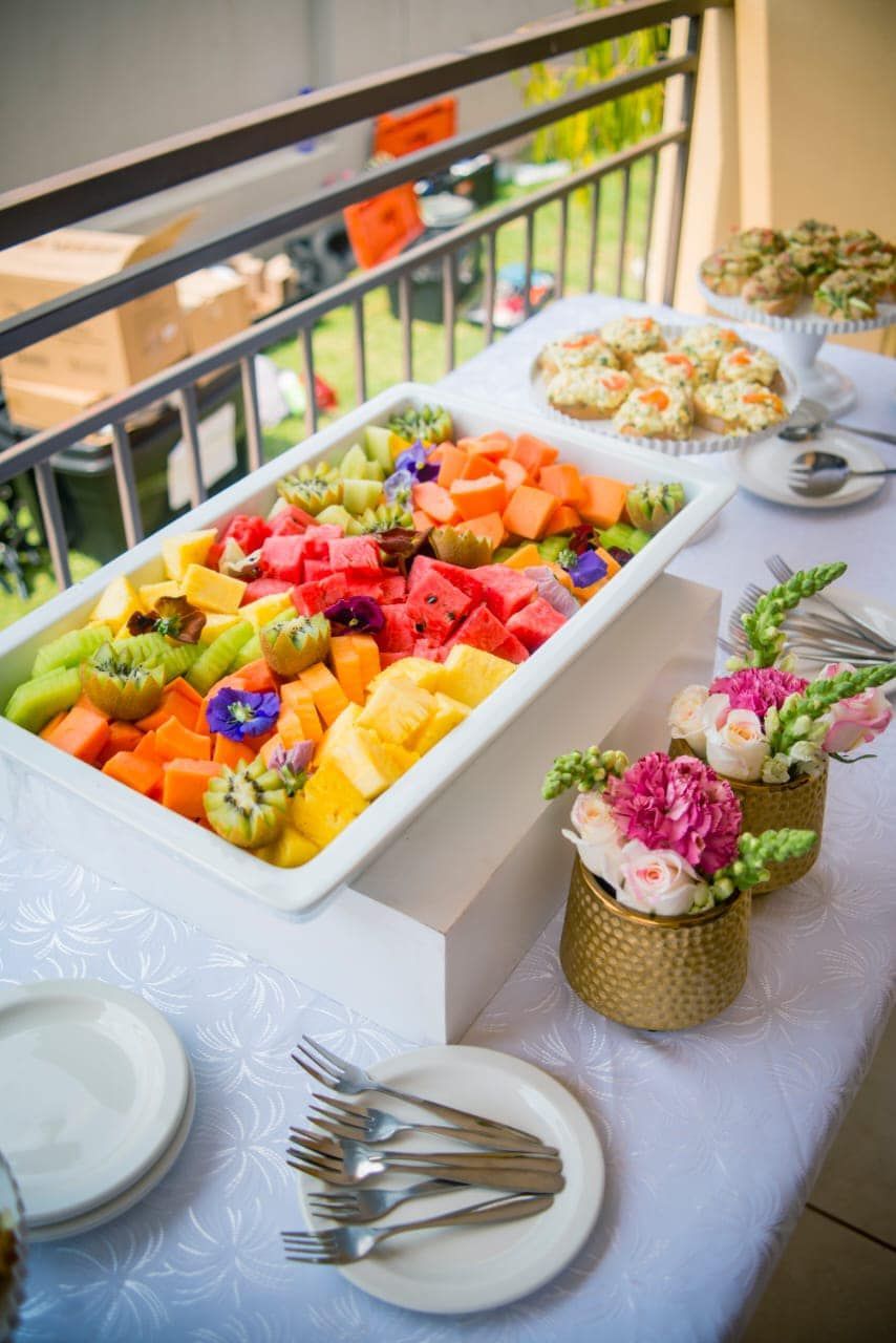 A buffet table with a variety of fruits and flowers on it