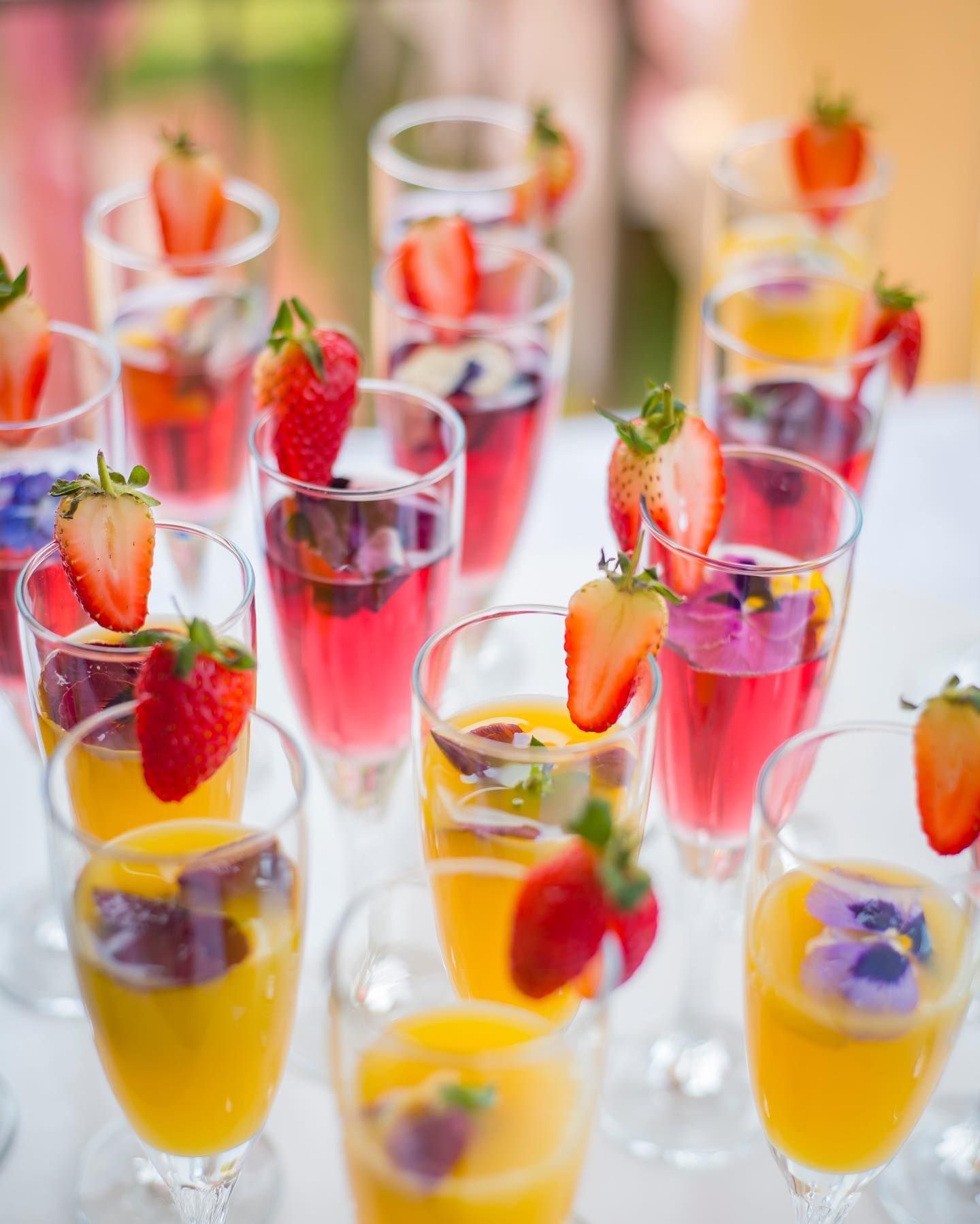 A bunch of wine glasses with strawberries on top of them