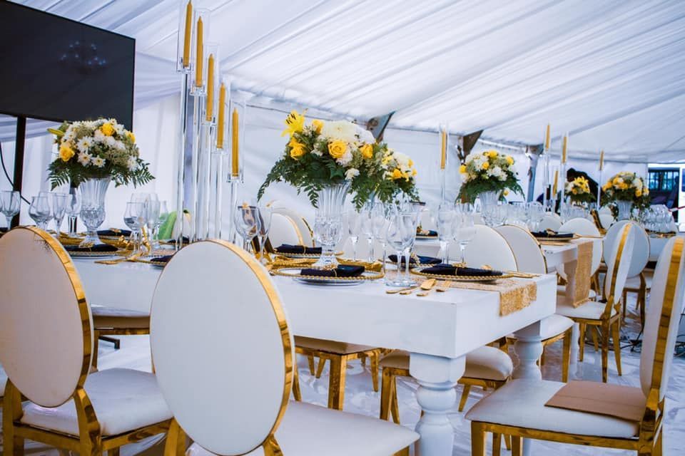 A table and chairs are set up for a wedding reception under a tent.