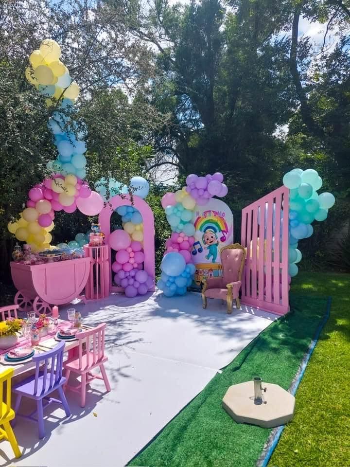 A backyard decorated for a birthday party with balloons and chairs.