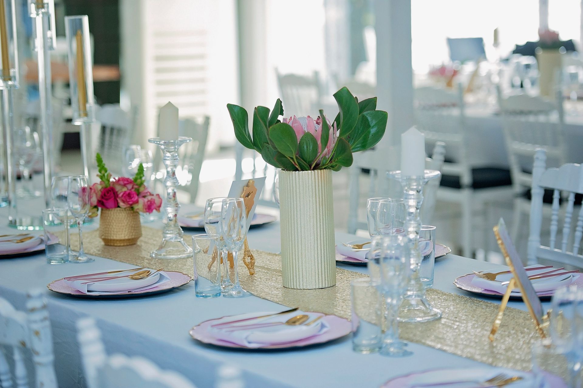 A table set for a wedding reception with plates , glasses , vases and flowers.