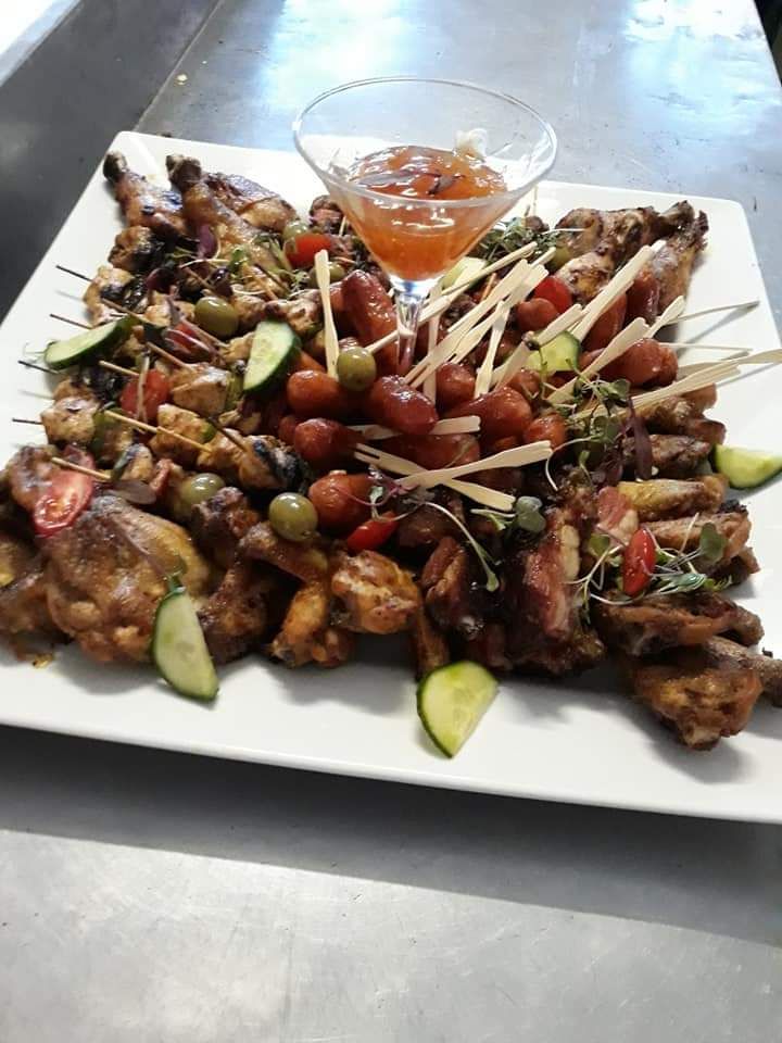 A white plate topped with meat and vegetables next to a martini glass.