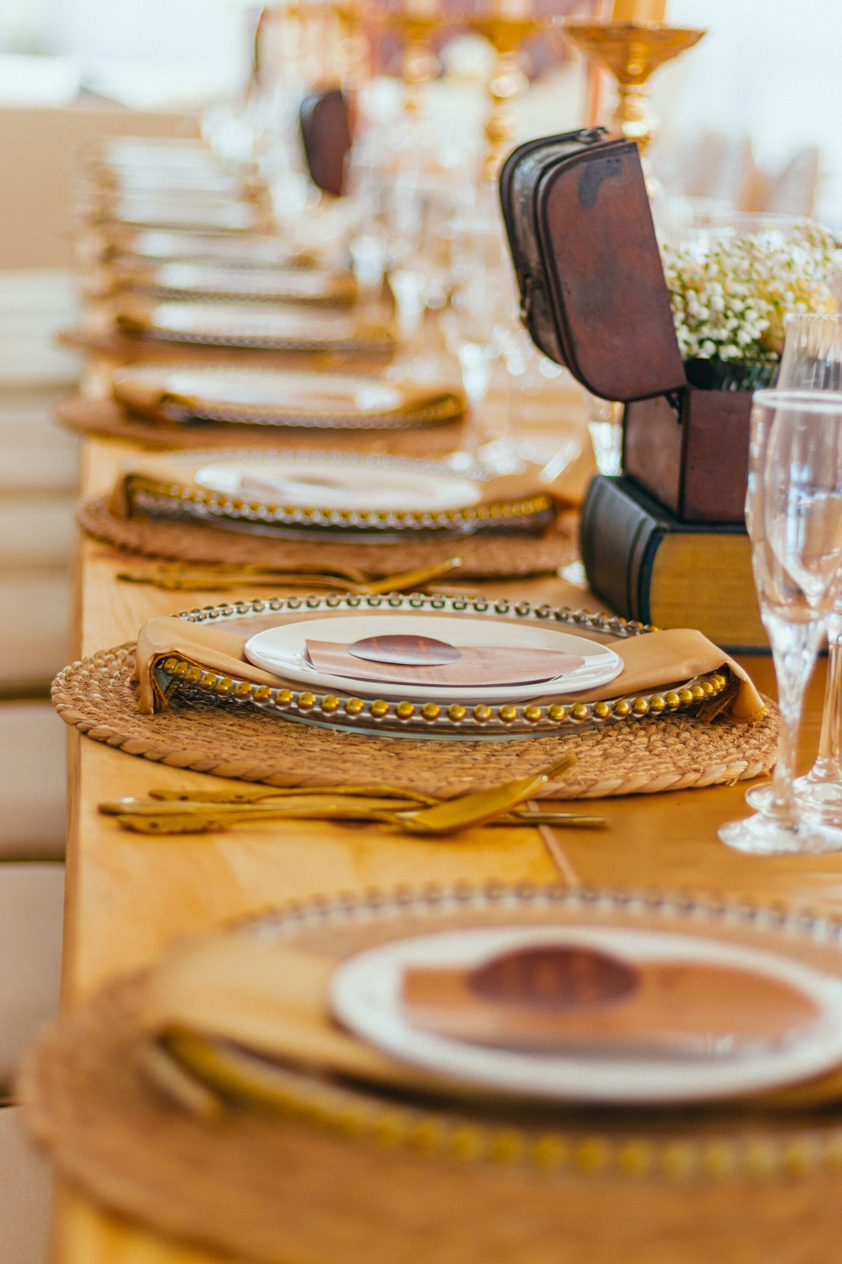 A long table set for a wedding reception with plates , utensils , and glasses.