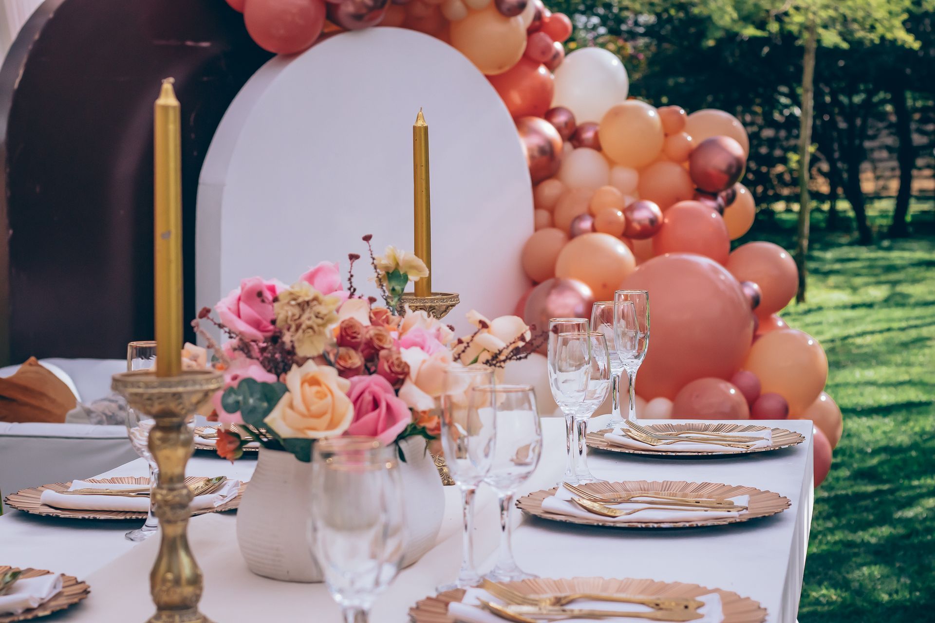 A table with plates , candles , flowers and balloons on it.