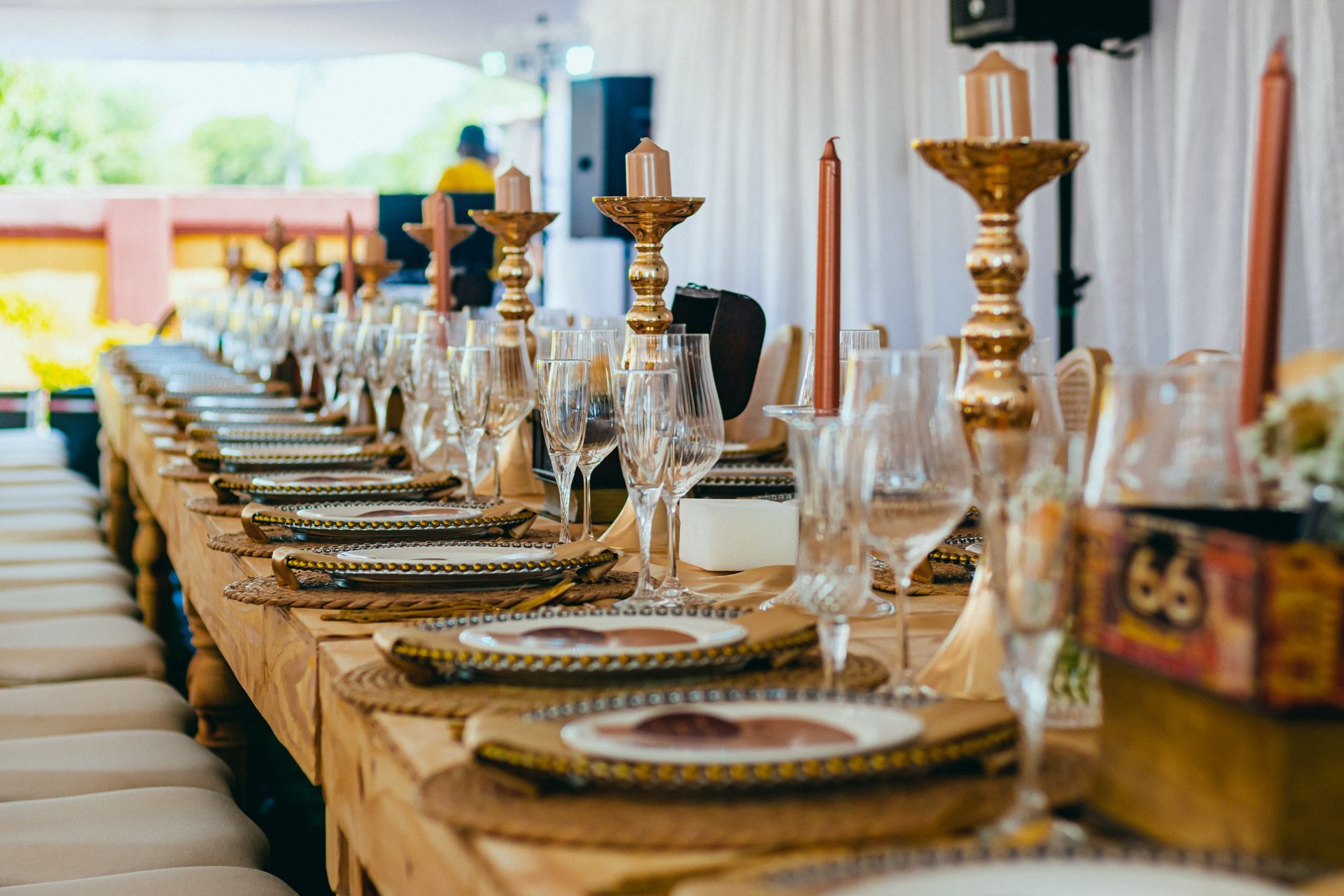 A long table set for a wedding reception with plates , wine glasses , and candles.
