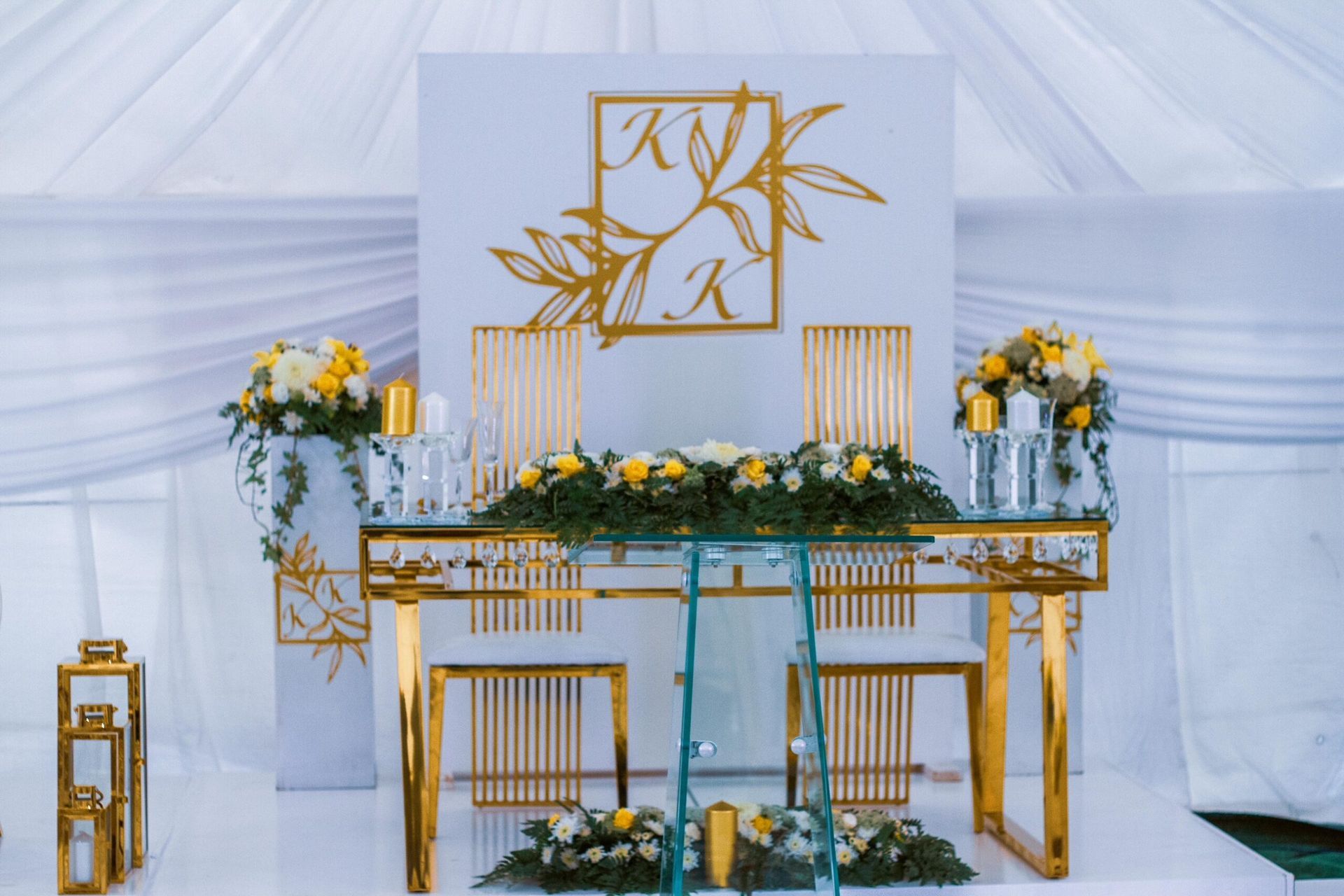 A table with flowers and candles on it in front of a white wall.