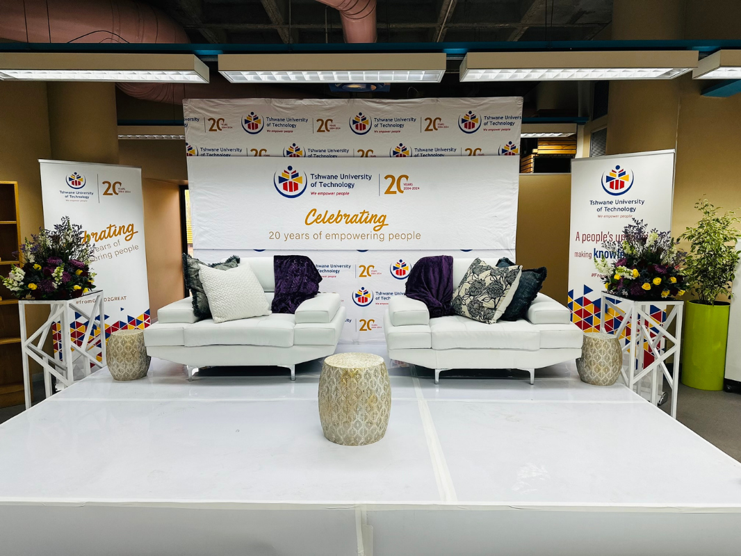 A room with a stage and a couch in it for a business celebrating their anniversary