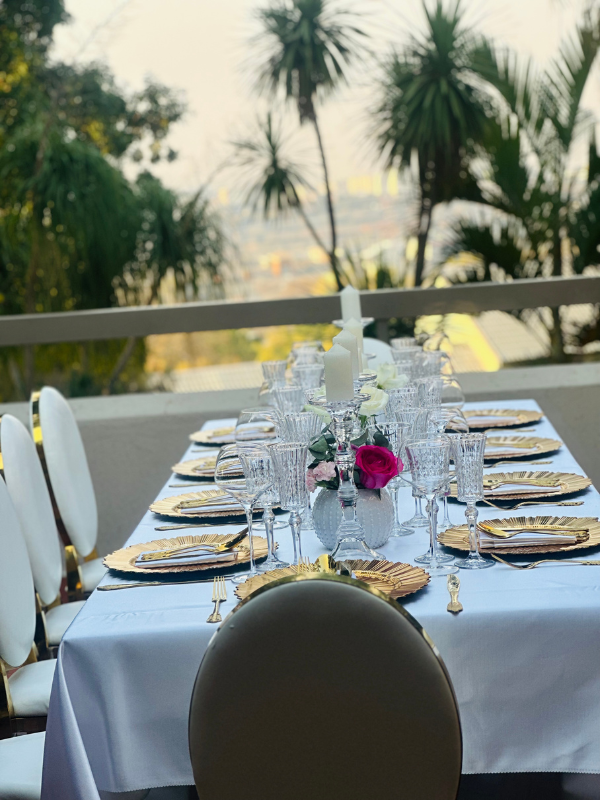 A long table with plates , glasses , and flowers on it.