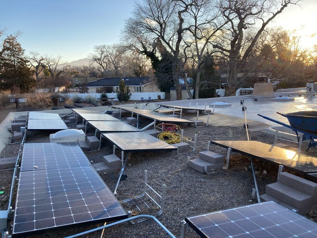 A bunch of solar panels are sitting on top of a gravel area.