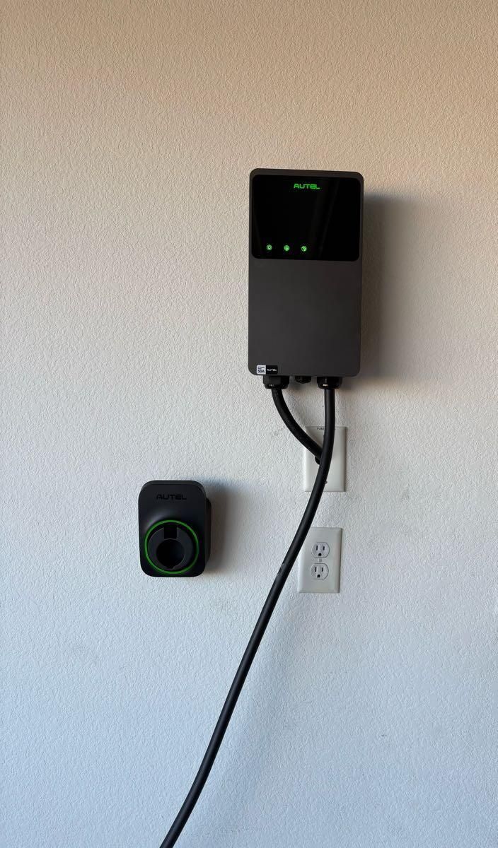 A charger is plugged into a wall next to a socket.
