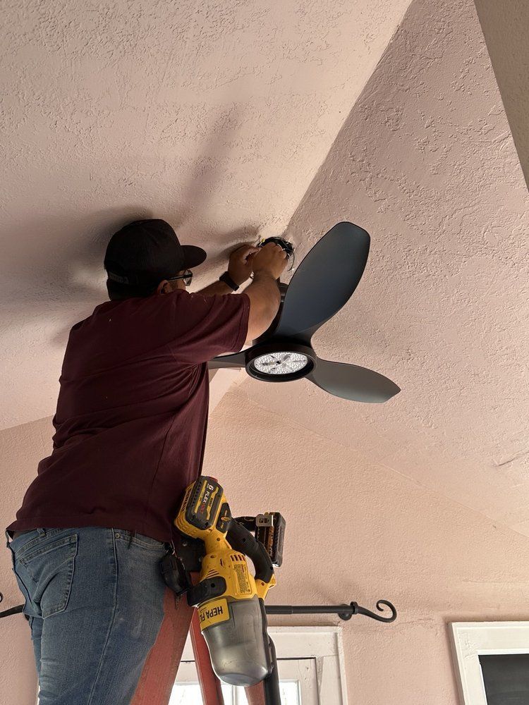 A man is installing a ceiling fan in a living room.