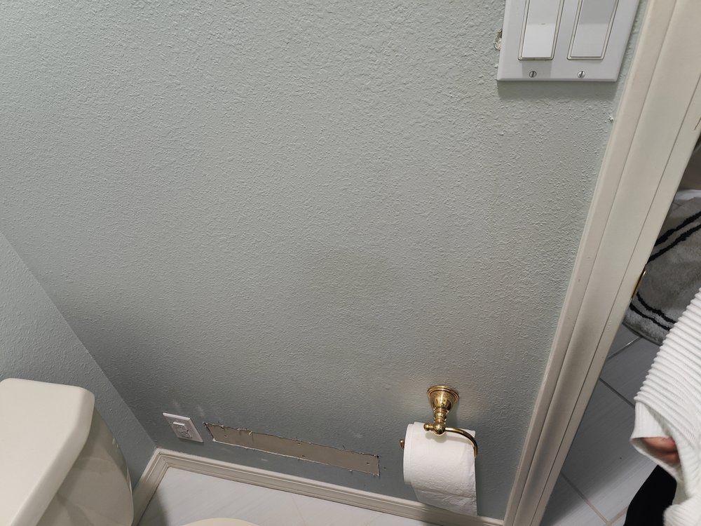 A bathroom with a toilet , toilet paper holder , and light switch.