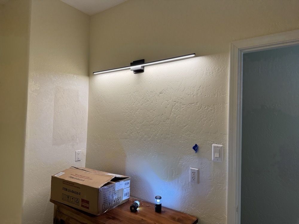 A box is sitting on a wooden table next to a wall with a light on it.