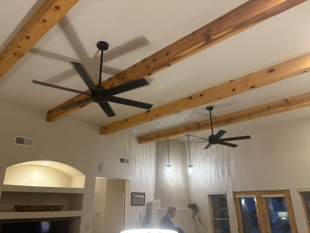 A living room with a ceiling fan and wooden beams