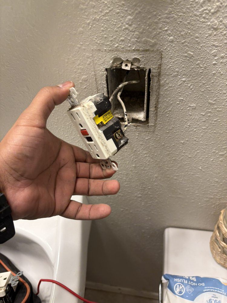 A person is holding a light switch in their hand in a bathroom.