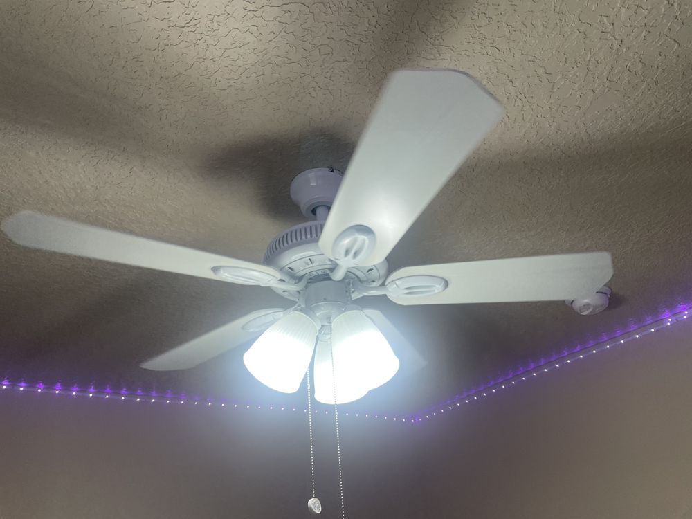 A white ceiling fan is hanging from the ceiling of a room.