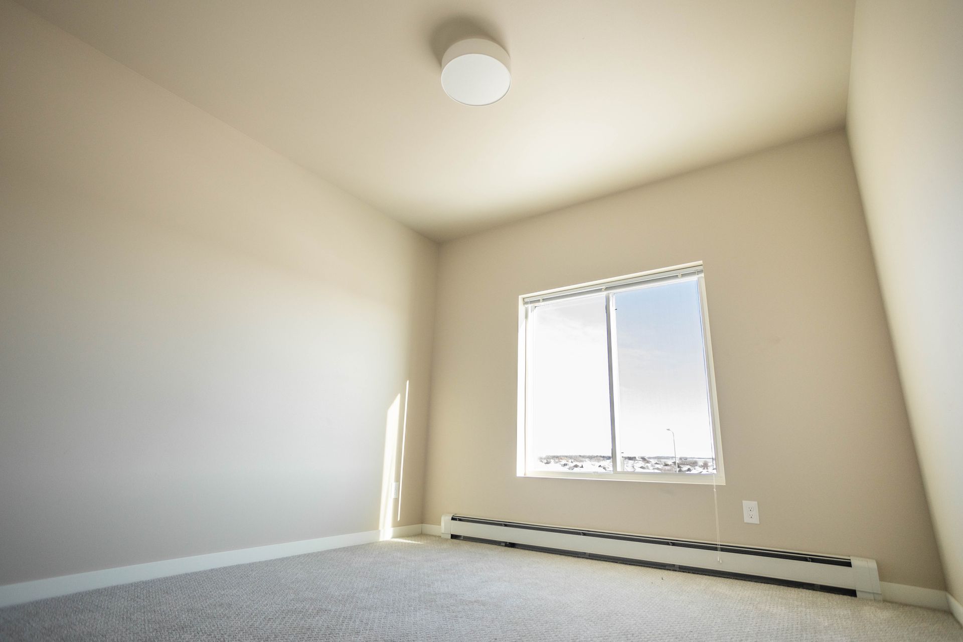 An empty room with a window and a ceiling light