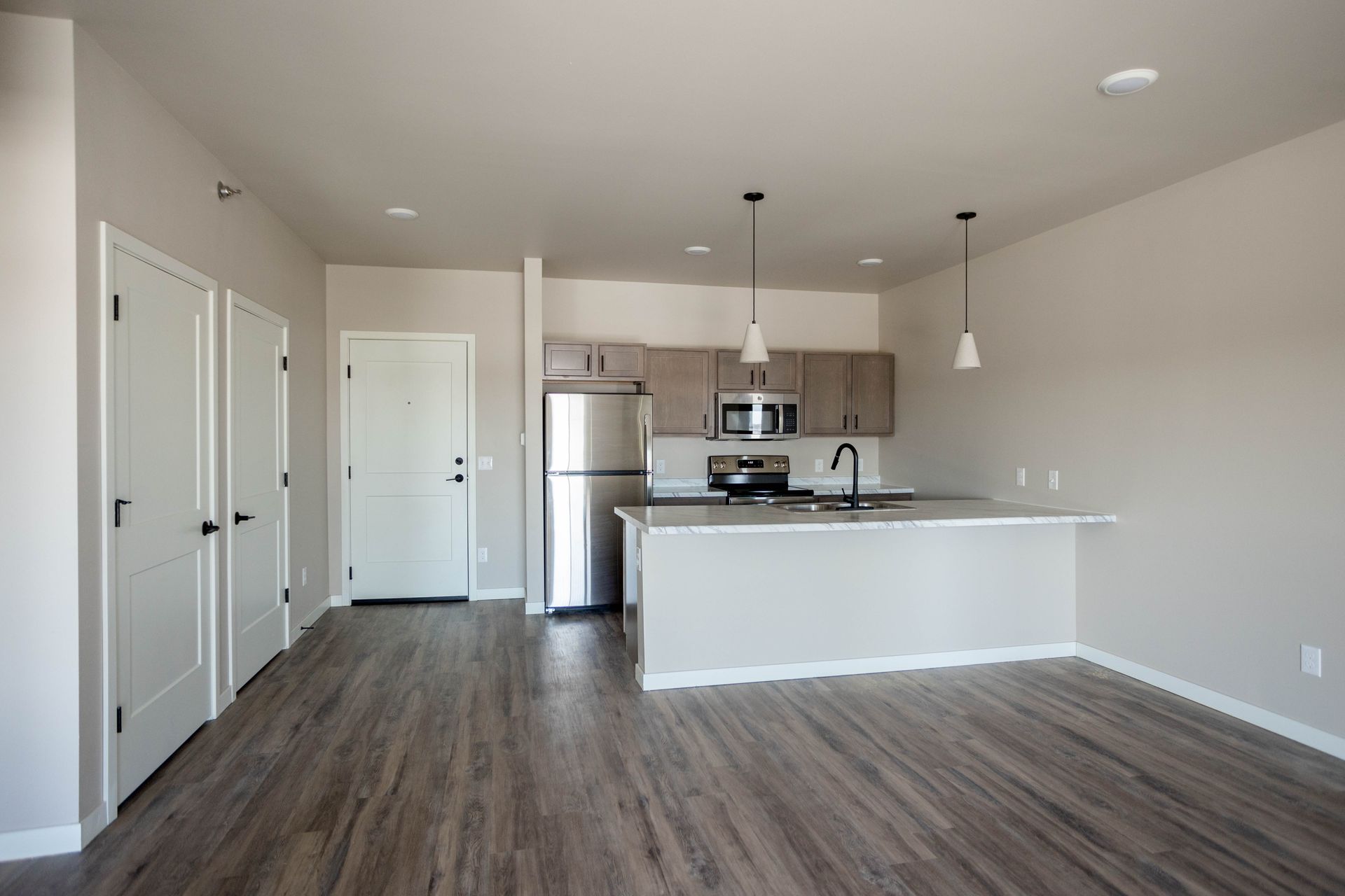 An empty apartment with a kitchen and a refrigerator