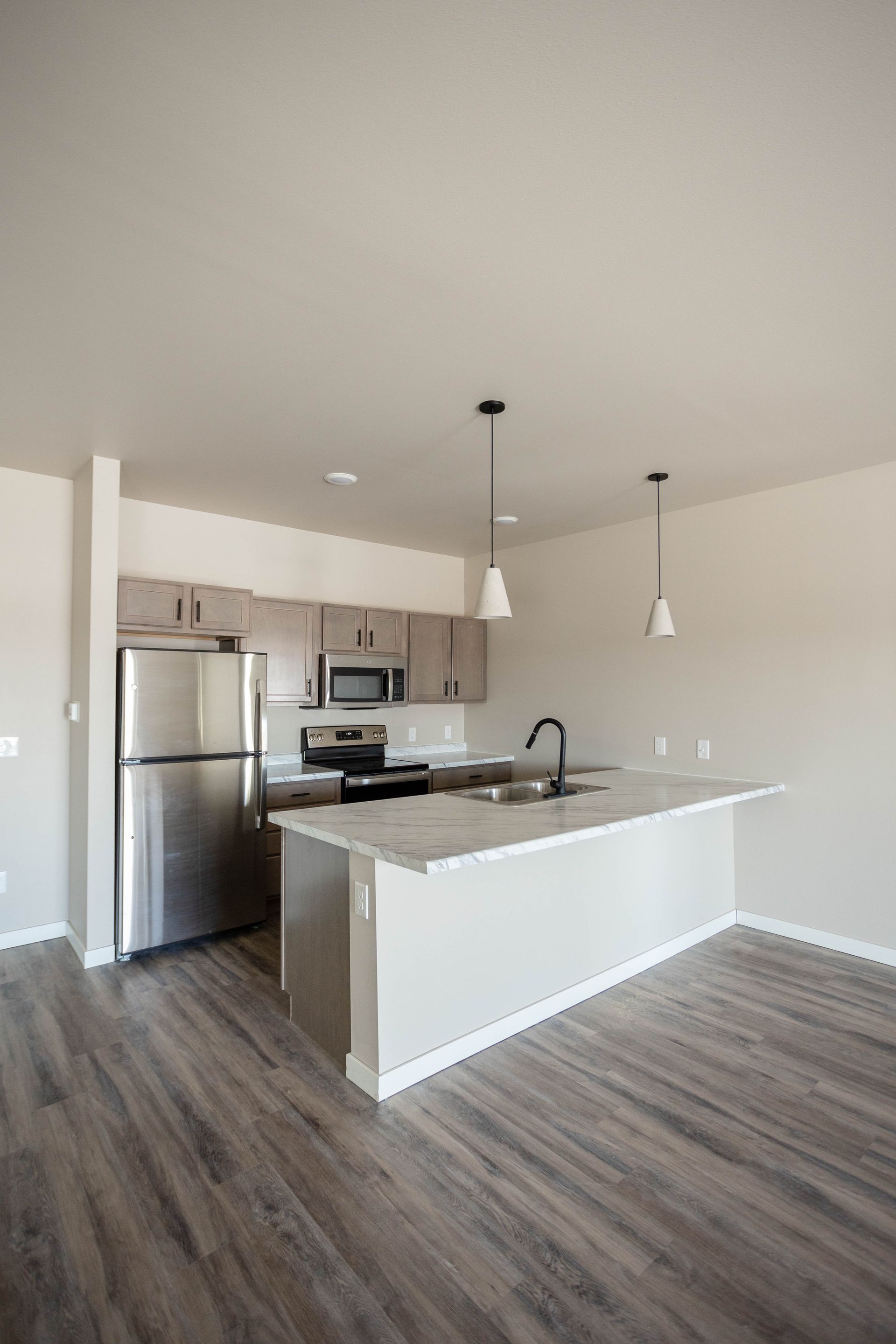 An empty kitchen with stainless steel appliances and a large island.