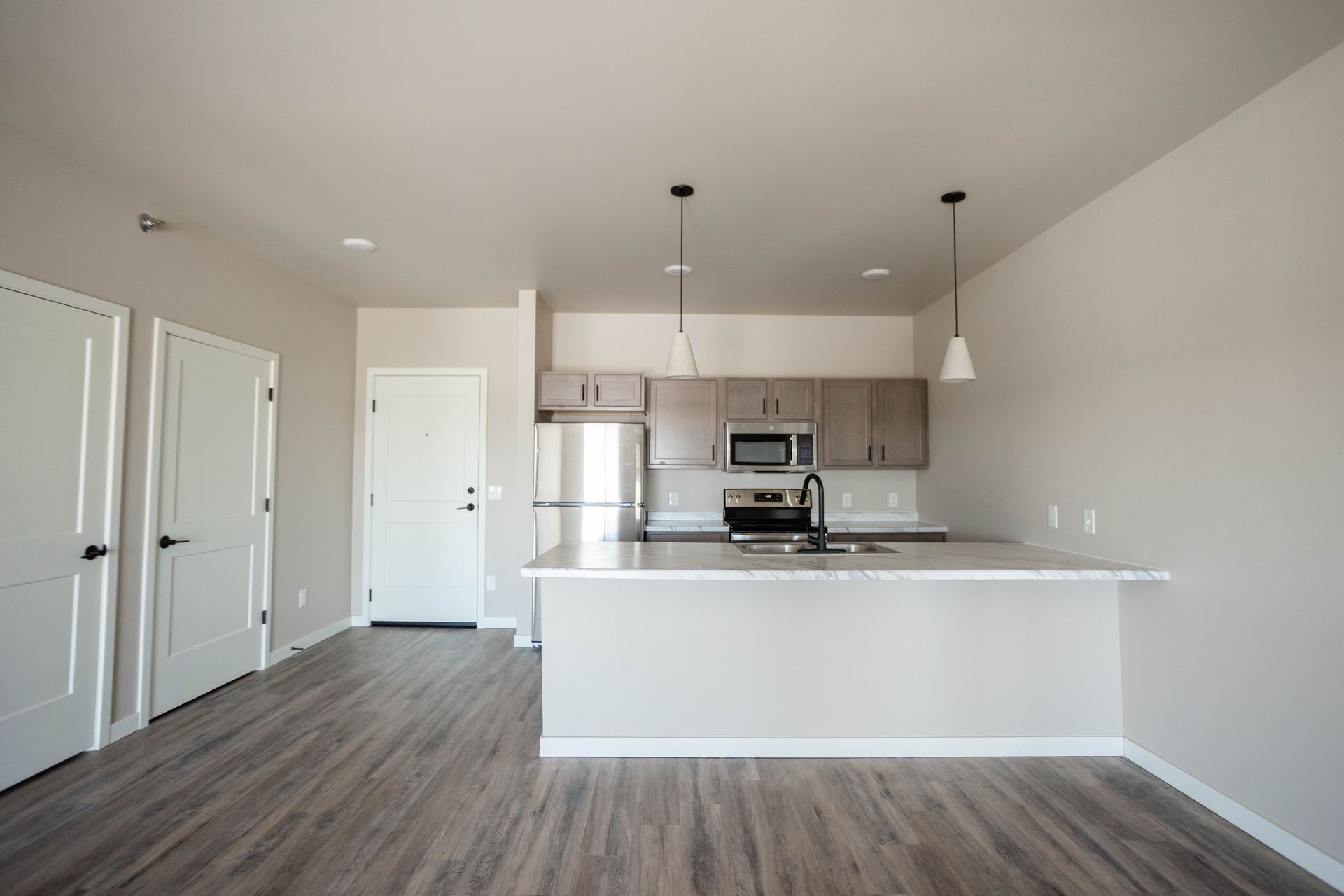 An empty apartment with a kitchen and stainless steel appliances