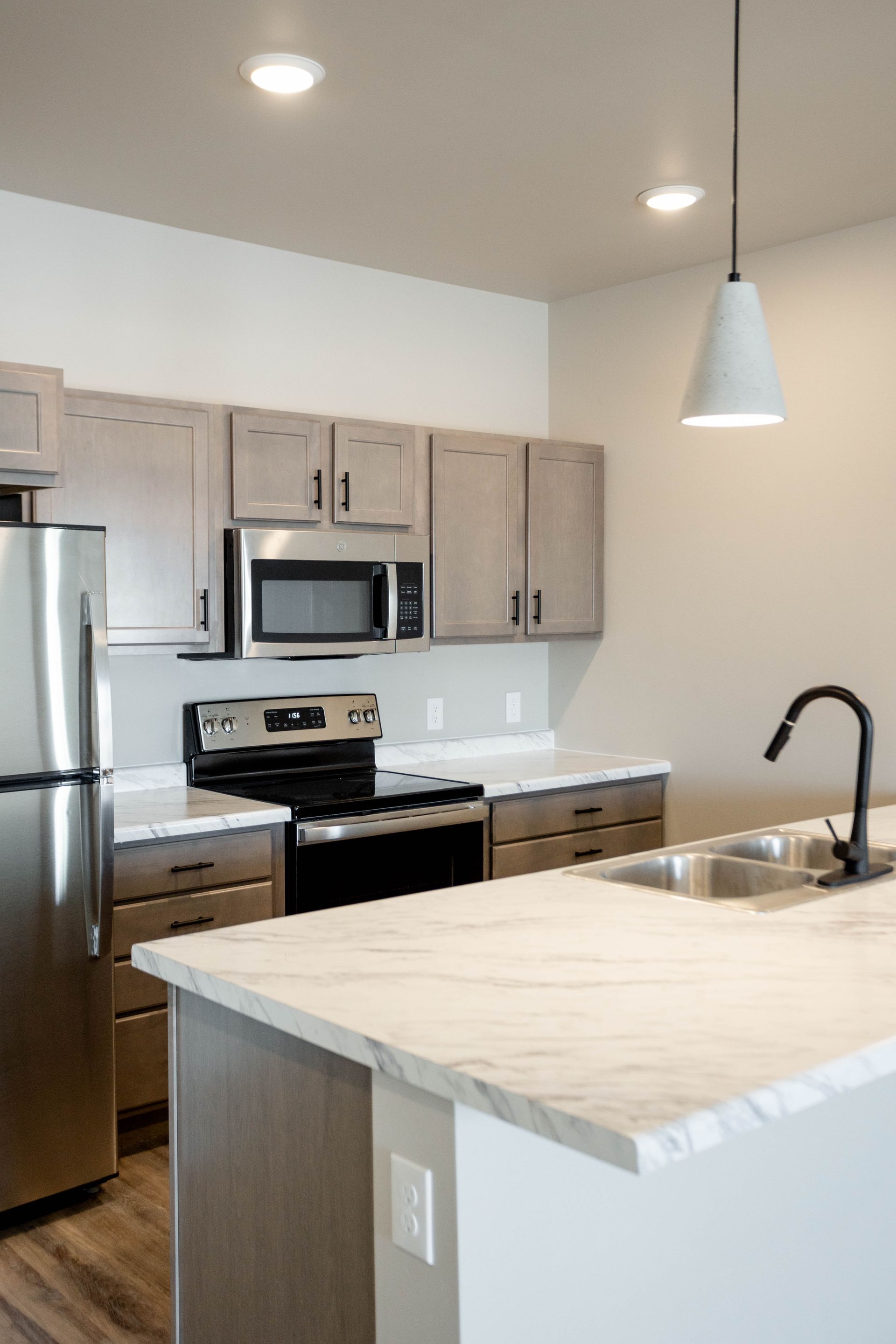 A kitchen with a stainless steel refrigerator , stove , microwave and sink.