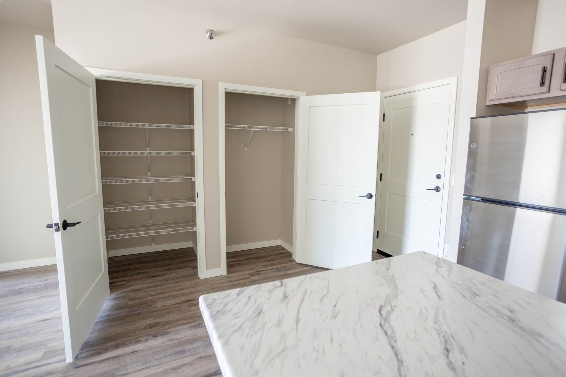 A kitchen with a refrigerator and a marble counter top.