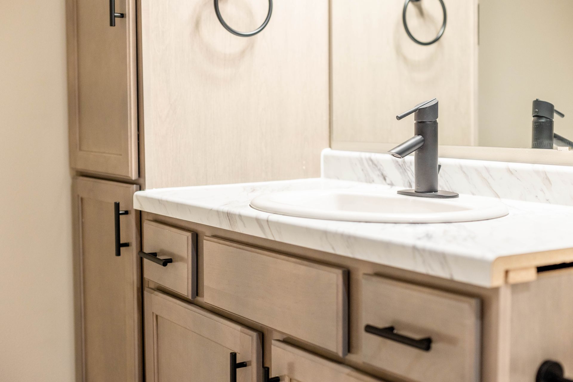 A bathroom with a sink , mirror and cabinets.