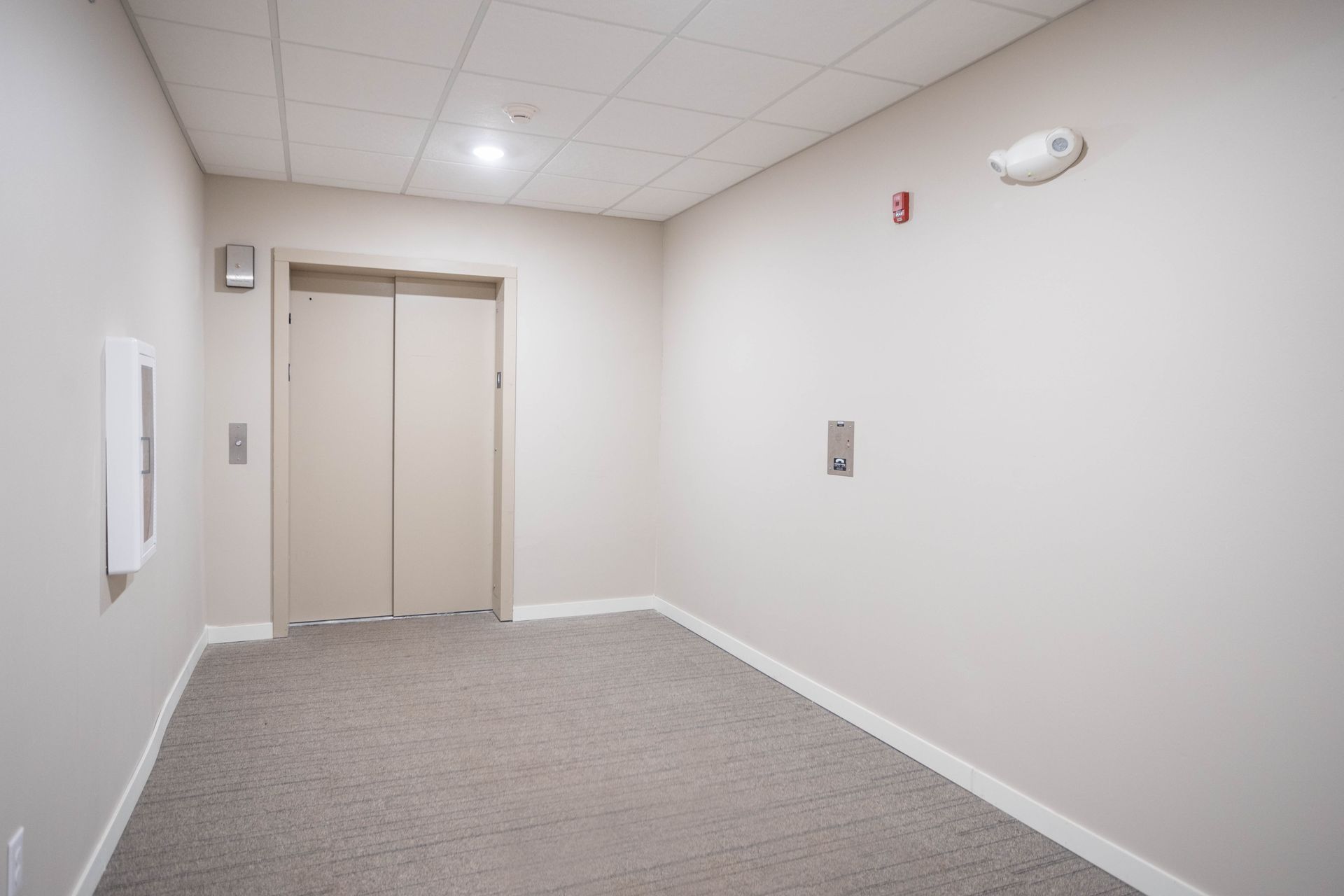 An empty hallway with an elevator in the middle of it.