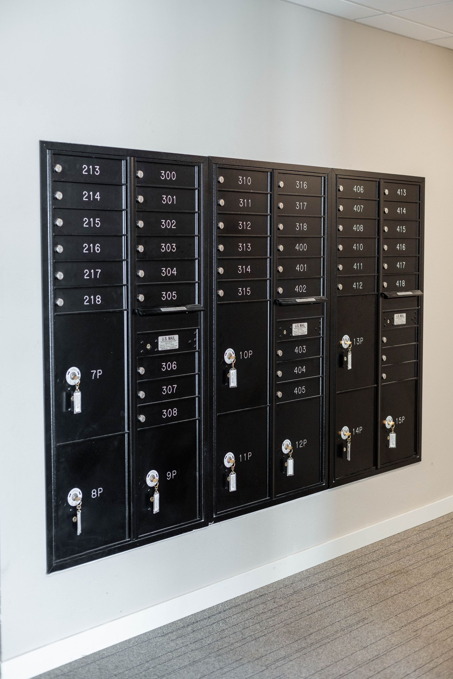 A row of black lockers are lined up on a wall.