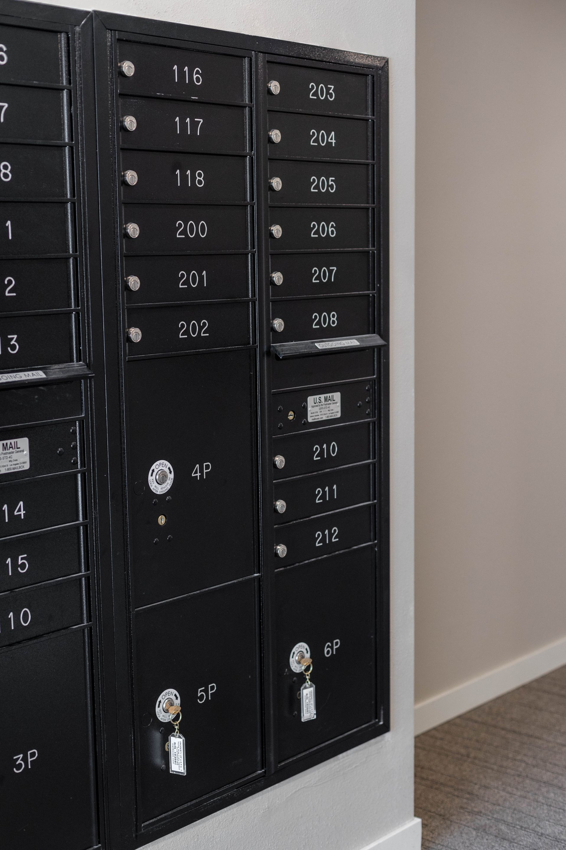 A row of black mailboxes with numbers on them on a wall.