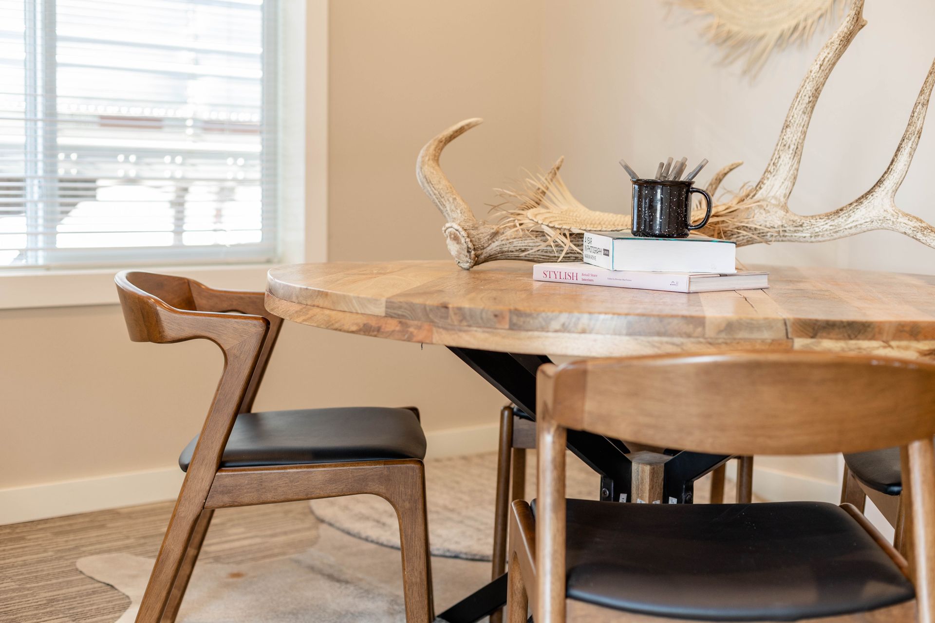 A dining room table and chairs with antlers on the wall.