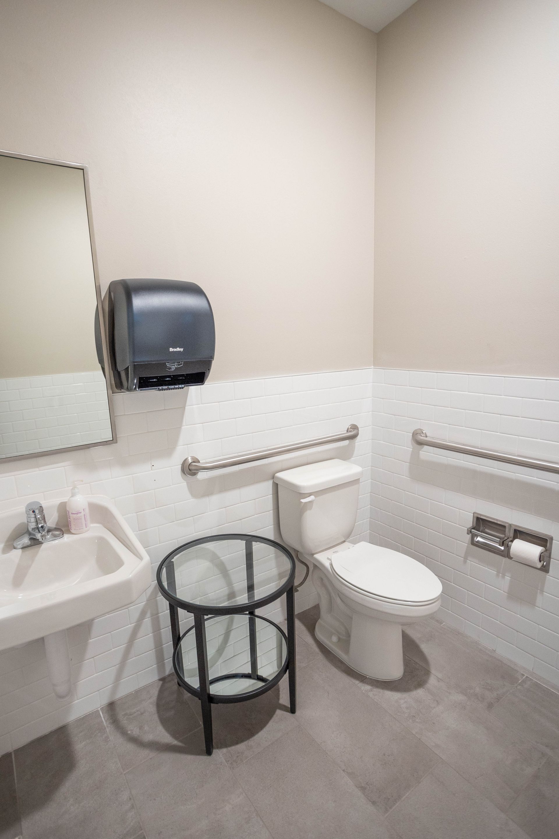 A bathroom with a toilet , sink and mirror.