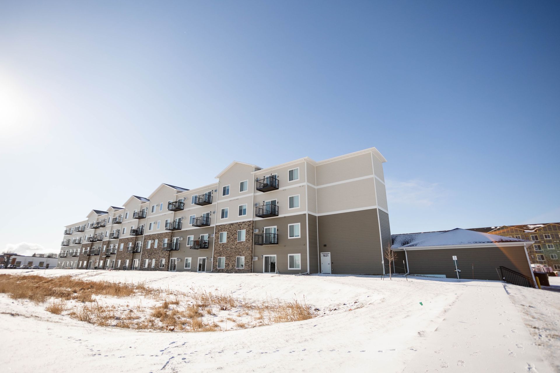 A large apartment building with snow on the ground in front of it