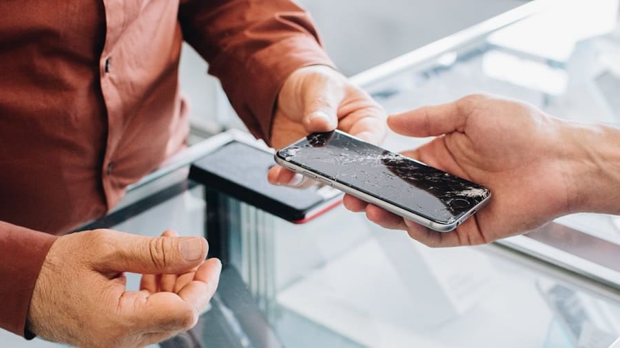 A man is giving a broken cell phone to another man.