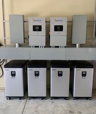 Solar power system with inverters, batteries, and electrical panels mounted on a wall.