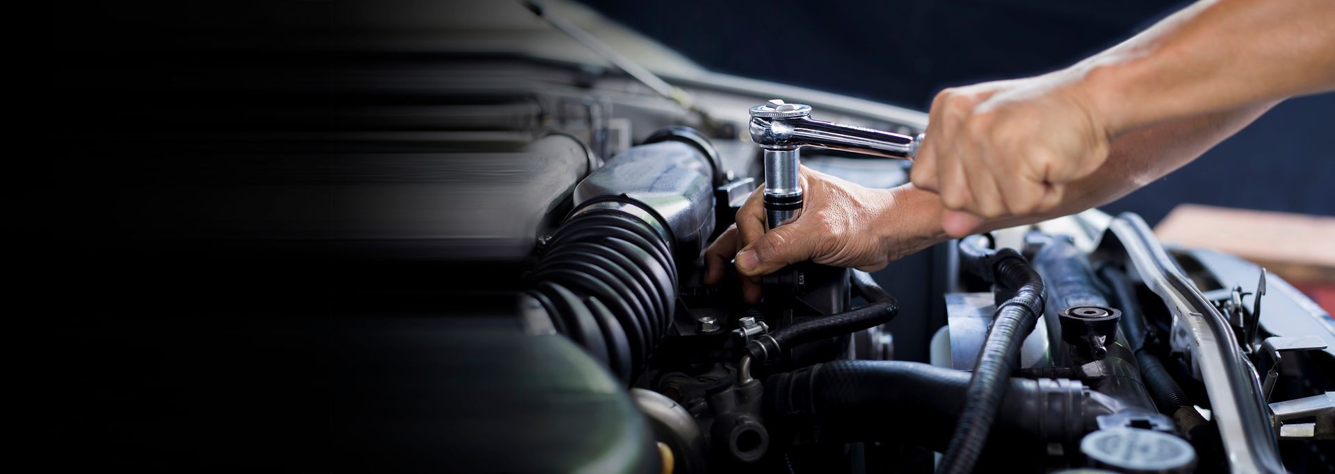 Mechanic working on a car engine with a wrench.