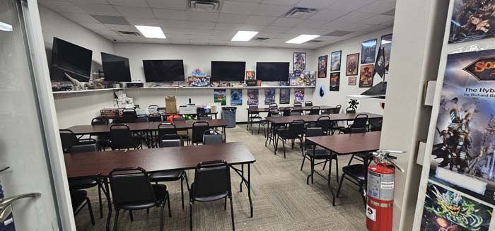 A game store with tables, chairs, TVs, posters on the wall, and a fire extinguisher.
