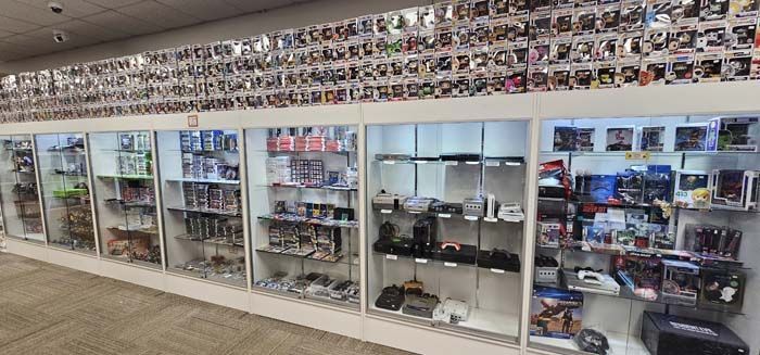 A store displaying video games and merchandise in glass display cases. A wall is covered in photos.