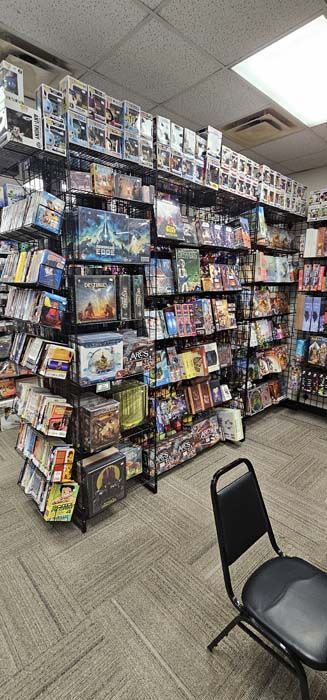 A retail store interior with shelves filled with board games, and a chair in the foreground.