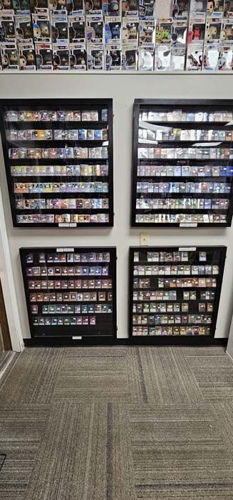 Four black display cases filled with small items on a wall, above carpeted floor.