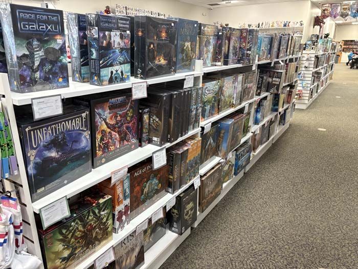 Rows of board games on white shelves in a brightly lit store.
